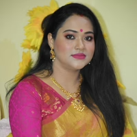 A woman in pink and yellow saree wearing gold-plated necklace and earrings
