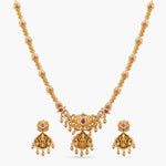 A picture of an Indian antique gold plated necklace set with a Lakshmi pendant and lotus motifs. The earrings are stud style with matching red gemstones.