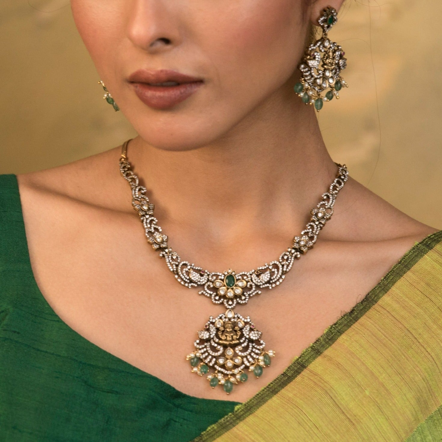 A picture of an Indian artificial gold plated necklace set with floral designs,Cubic Zirconia and red gemstones , and pearl embellishments.