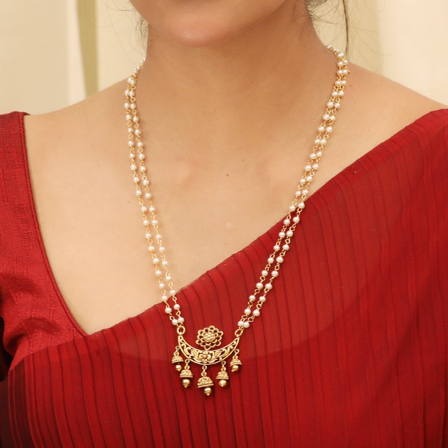 A picture of an Indian artificial gold plated necklace set with a pendant in moon shaped pedant and antique balls.