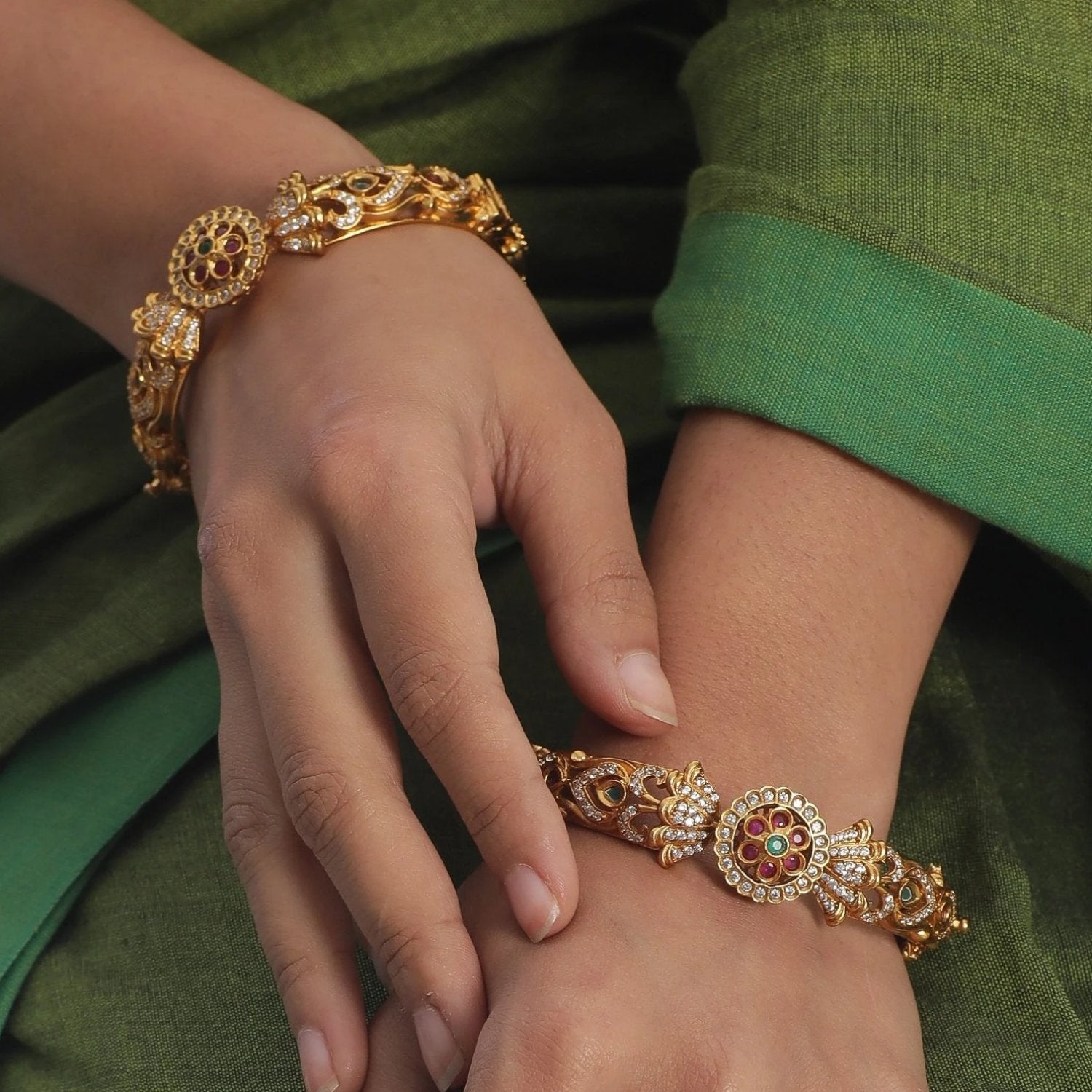 A picture of Indian artificial gold bangles with colorful rhinestones and emeralds.