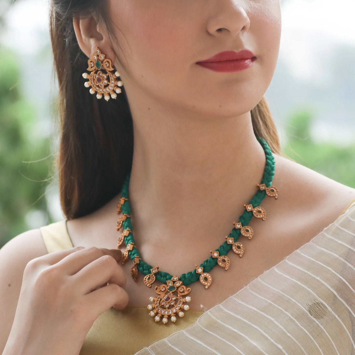 A picture of an Indian artificial jewellery set with a gold necklace, pendant, and matching earrings with intricate beadwork designs.
